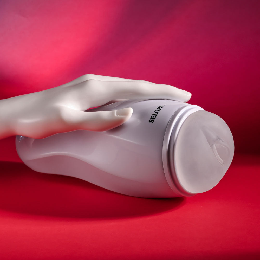 Hand holding the Selopa PLEASURE CAN - against a vibrant red background, showcasing its sleek design.