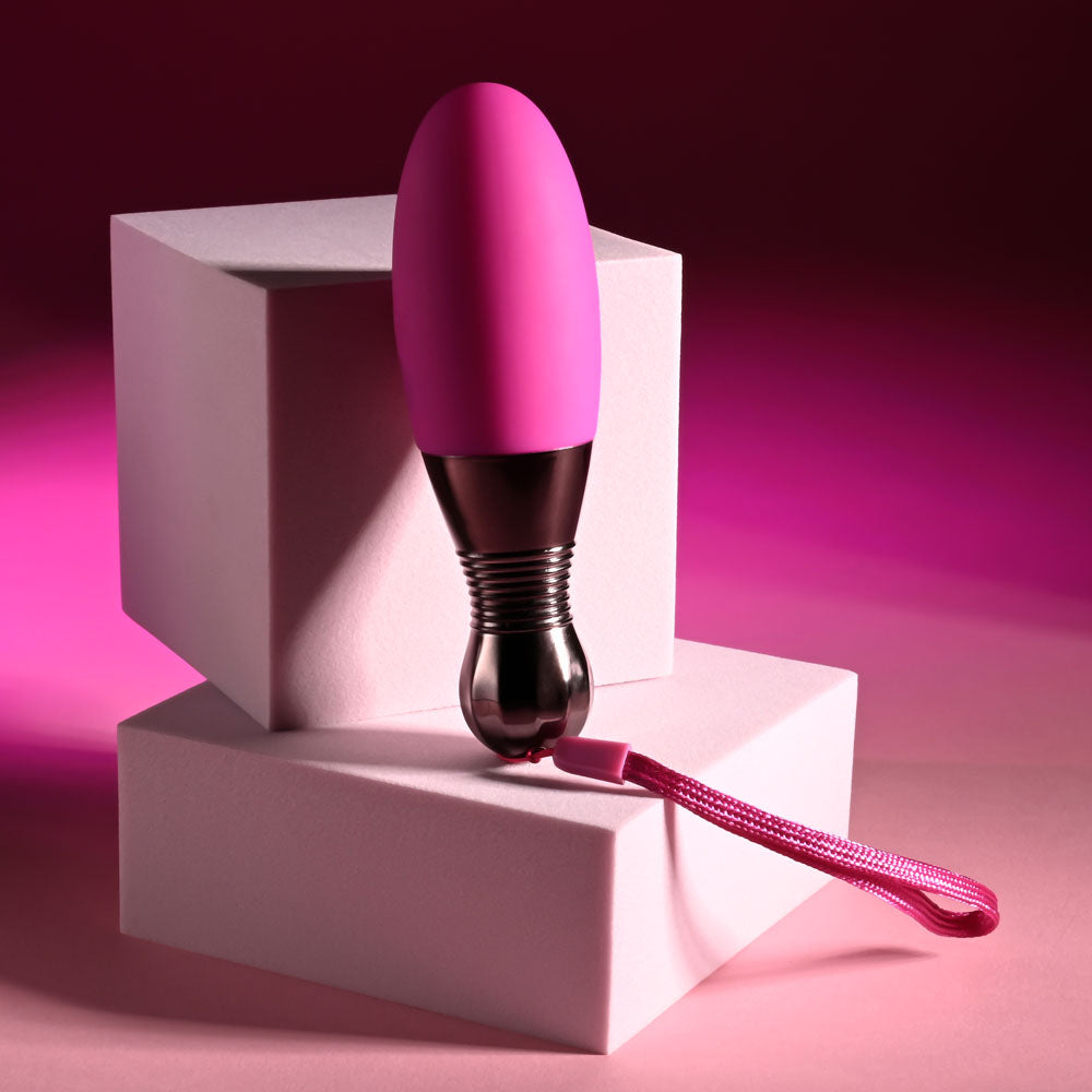 Selopa COMPANION -  11.9 cm USB Rechargeable Vibrating Egg in pink resting on white blocks with a safety retrieval cord