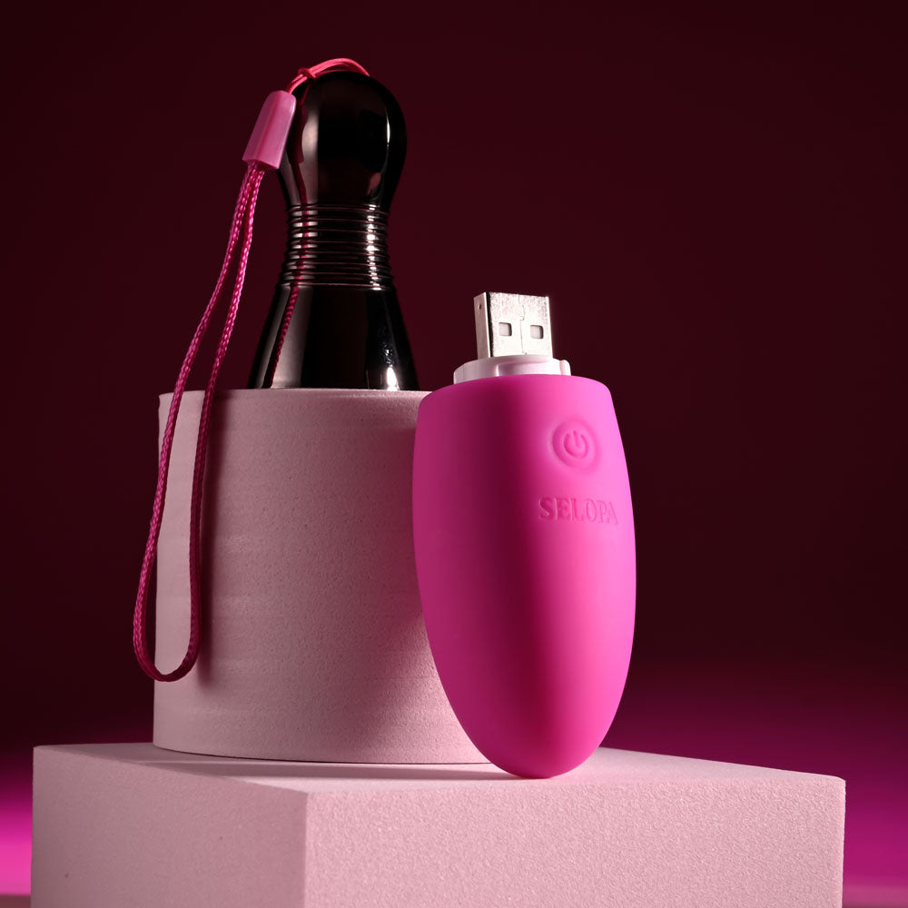 Selopa COMPANION -  11.9 cm USB Rechargeable Vibrating Egg displayed with chrome handle and USB connection on a pink pedestal.