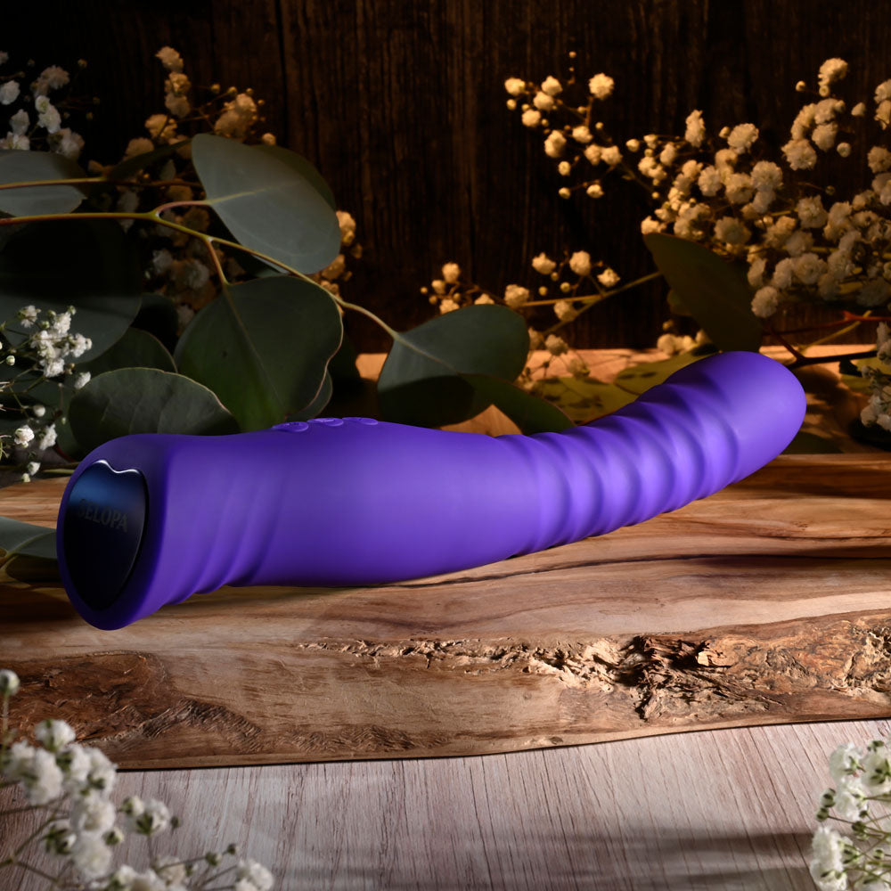 Selopa TRIXXXIE -  22.2 cm USB Rechargeable Vibrator on a wooden surface surrounded by flowers and greenery.