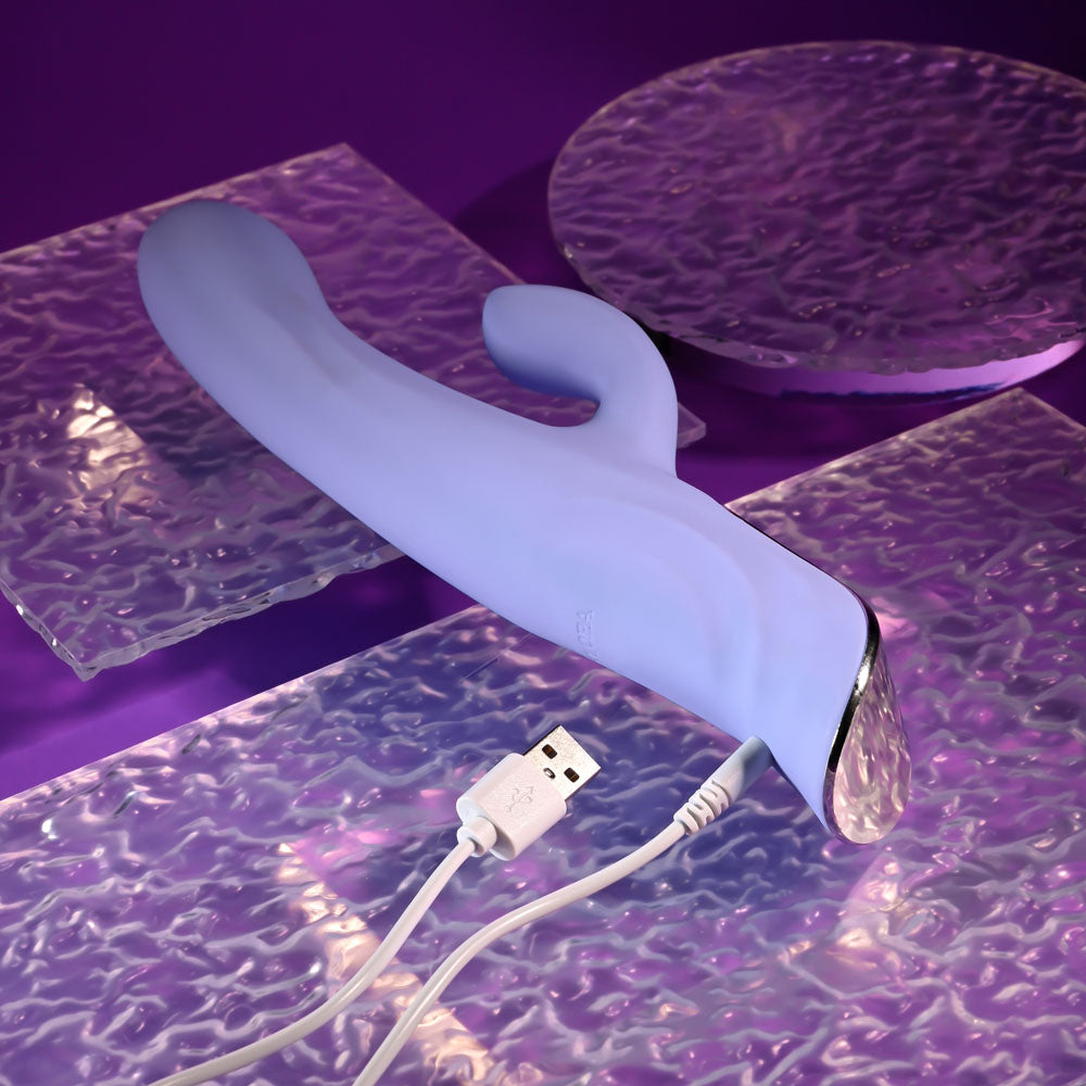 Evolved LAVENDER LOVE - 23.3 cm USB Rechargeable Rabbit Vibrator resting on a textured surface with USB cable.