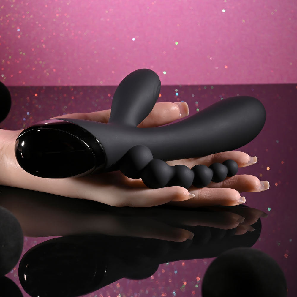 Selopa TRIPLE ACES -  19.7 cm USB Rechargeable Triple Stimulator Vibrator in a hand against a sparkly background.
