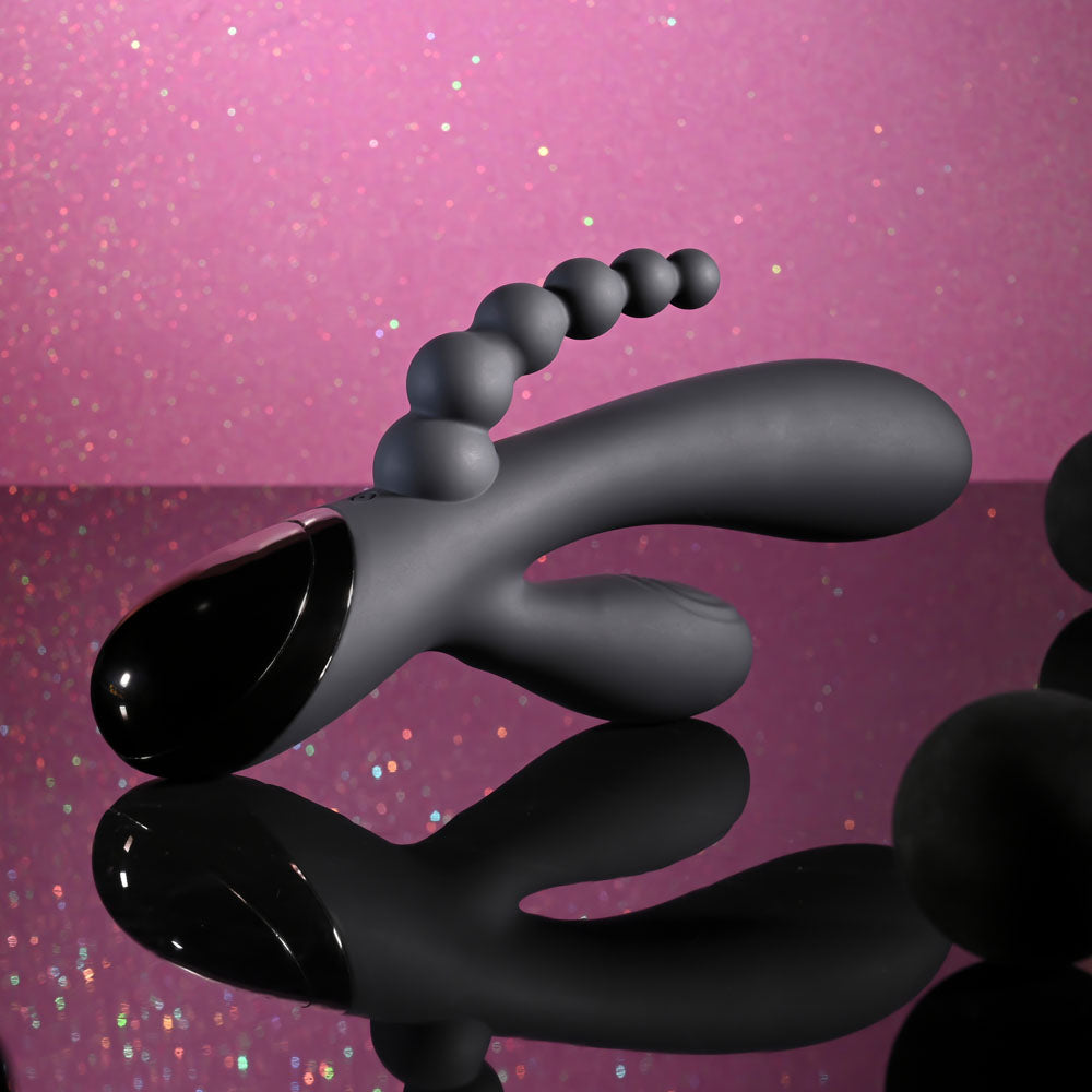 Selopa TRIPLE ACES - 19.7 cm USB Rechargeable Triple Stimulator Vibrator on a reflective surface with pink background.