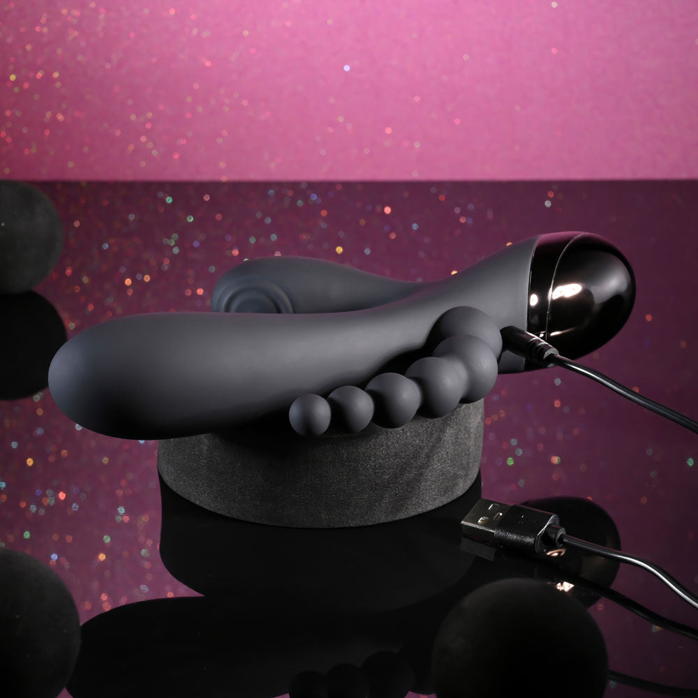 Selopa TRIPLE ACES - 19.7 cm USB Rechargeable Triple Stimulator Vibrator on a display with charging cable.