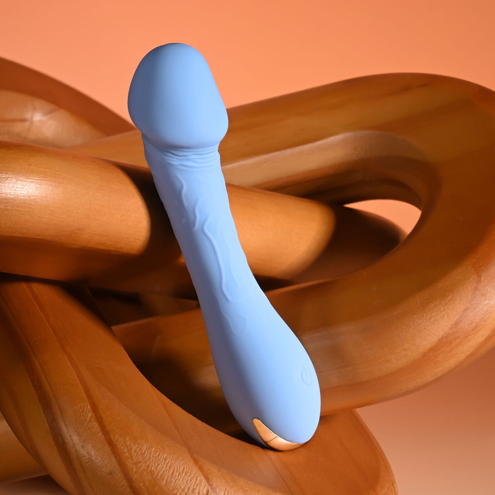 Selopa DAINTY DICK - Baby  11.9 cm USB Rechargeable Mini Vibrator positioned on wooden shapes, featuring a blue silicone design.