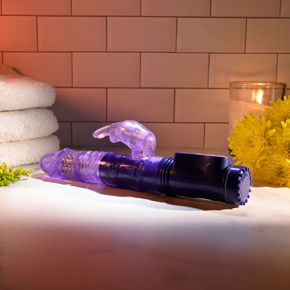 Selopa BUNNY THRUSTER - 24.8 cm Thrusting Rabbit Vibrator on a countertop with towels and candles.