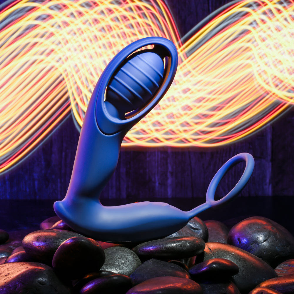 Zero Tolerance EXTRA MILE -  USB Rechargeable Vibrating Prostate Massager on smooth stones with colorful light trails.