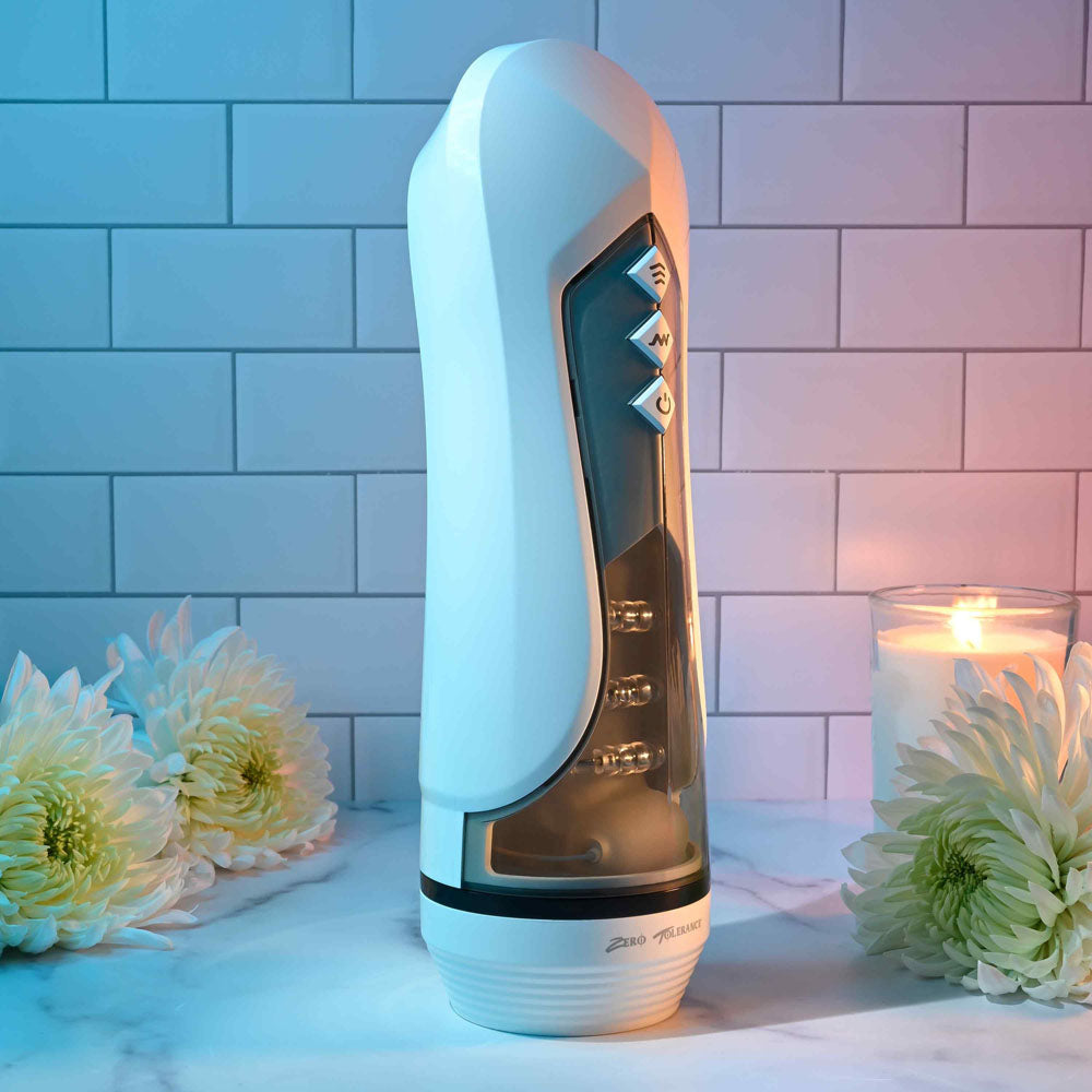 Zero Tolerance STROKING BUDDY - USB Rechargeable Vibrating & Thrusting Stroker on a neutral background with flowers and candles.