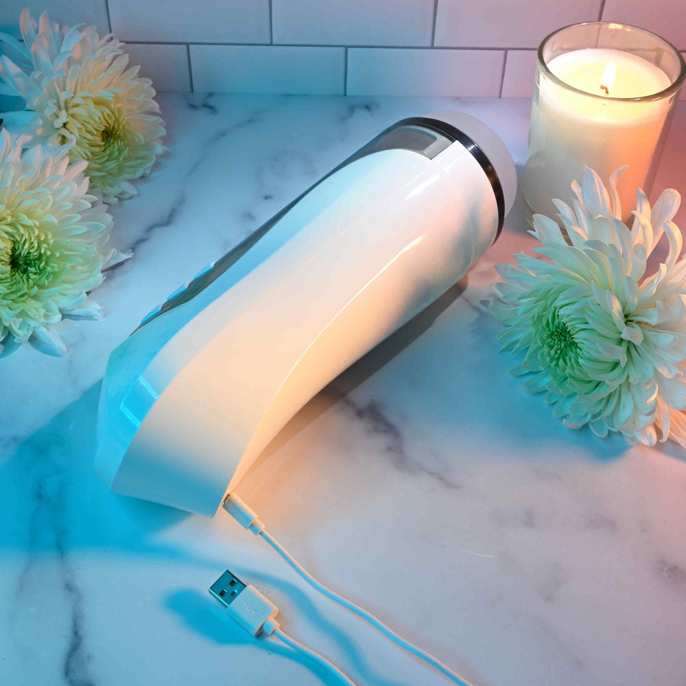 Zero Tolerance STROKING BUDDY - USB Rechargeable Vibrating & Thrusting Stroker on marble surface with flowers and candle.